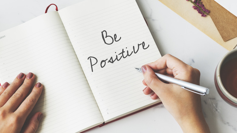 woman writing "be positive"