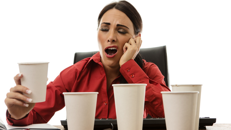 woman yawning with empty coffee cups