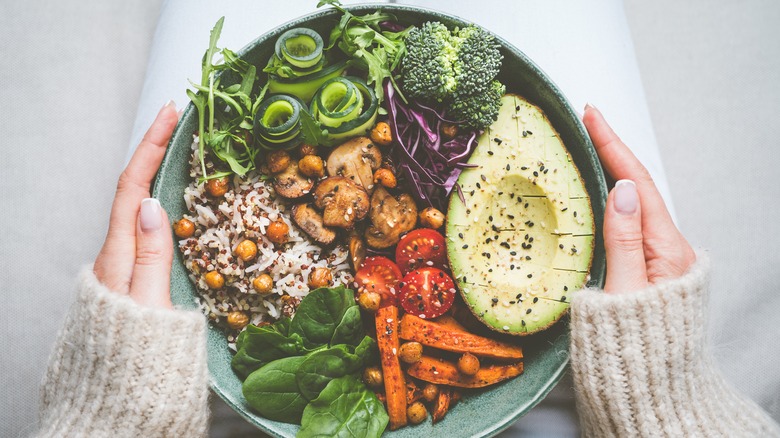 hands holding bowl with healthy food