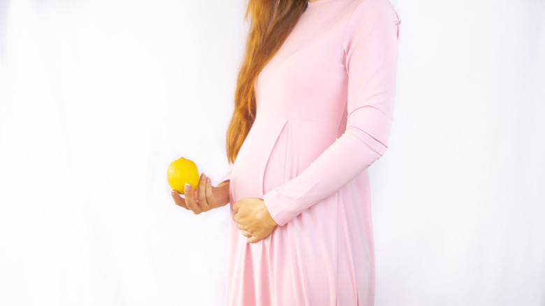 Pregnant woman holding lemon