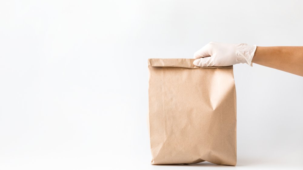 Gloved hand with a paper bag