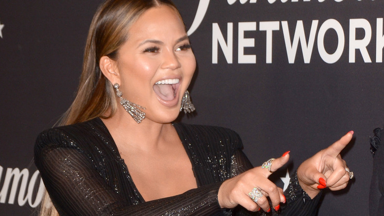 Chrissy Teigen pointing and laughing