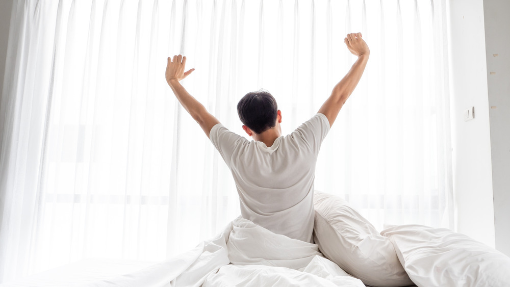 Man waking up and stretching in bed