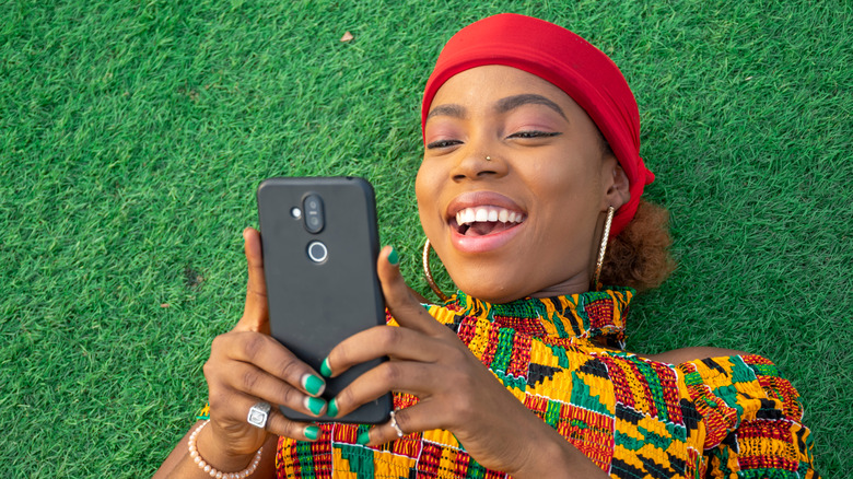 woman in grass smiling at phone