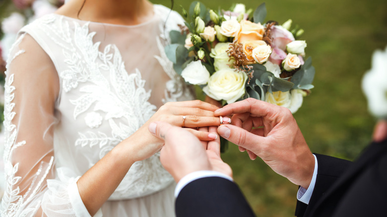 bride and groom putting on wedding bands