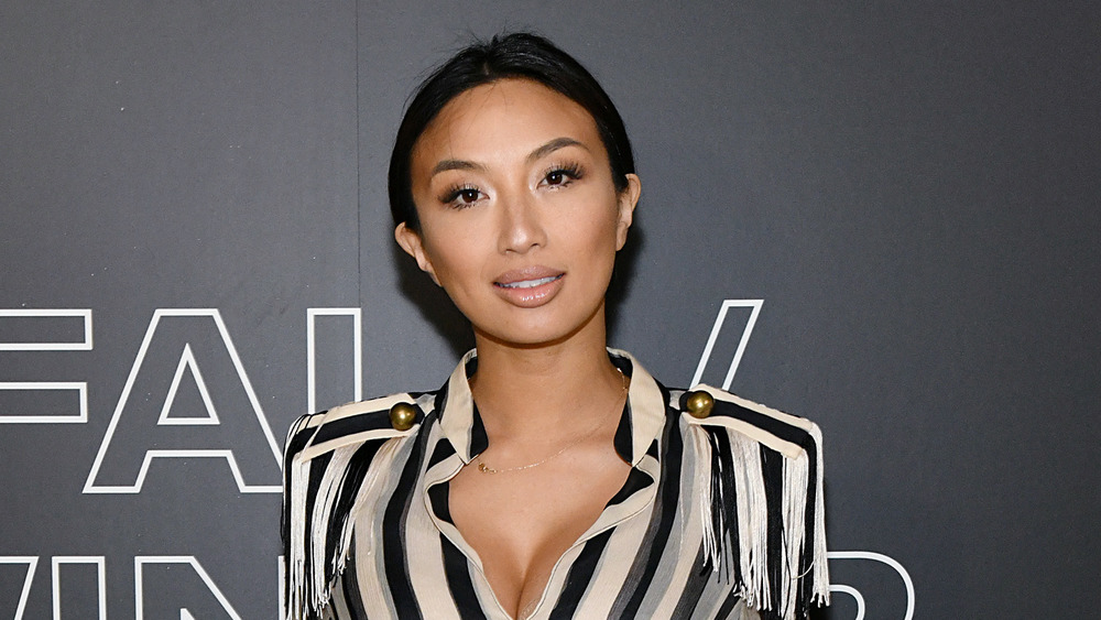 Jeannie Mai posing in a striped shirt