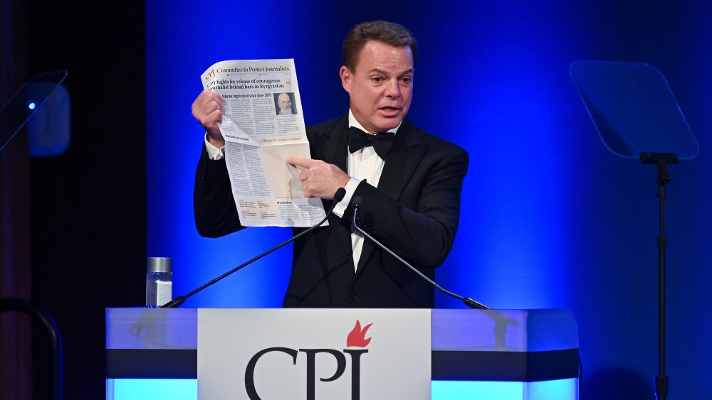 Shepard Smith holding up a newspaper 