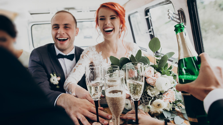 Bride and groom drinking champagne in car