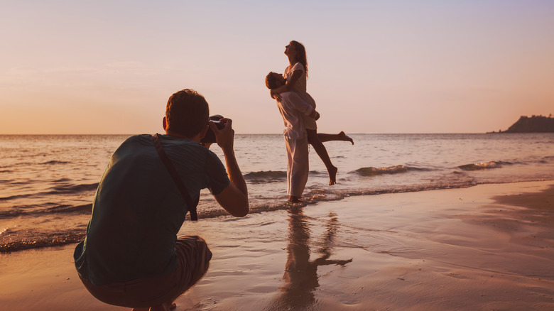 person photographing couple on the beach