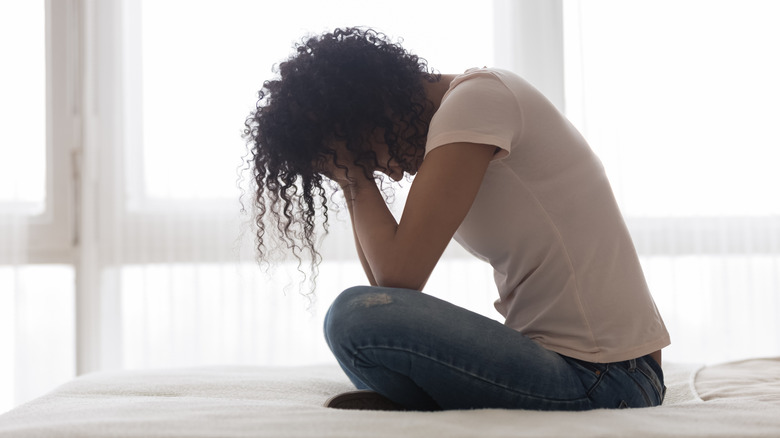 Curly-haired girl sitting, head down