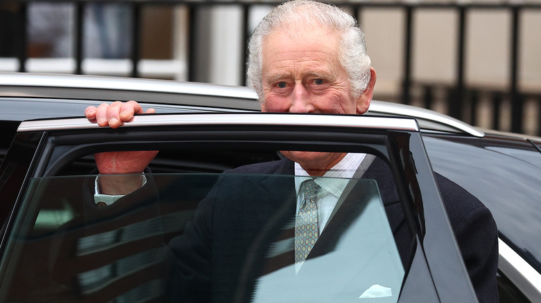 King Charles peeking out from behind a car door