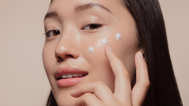 A woman applies face cream