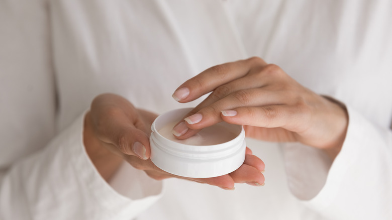 Woman dipping her fingers into a skincare product