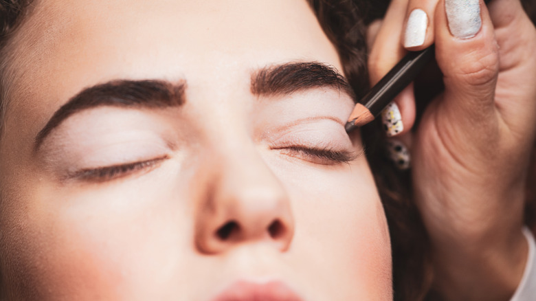 Artist applying eyeliner to woman