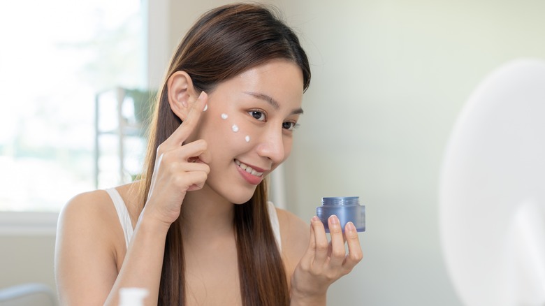 happy woman putting on sunscreen