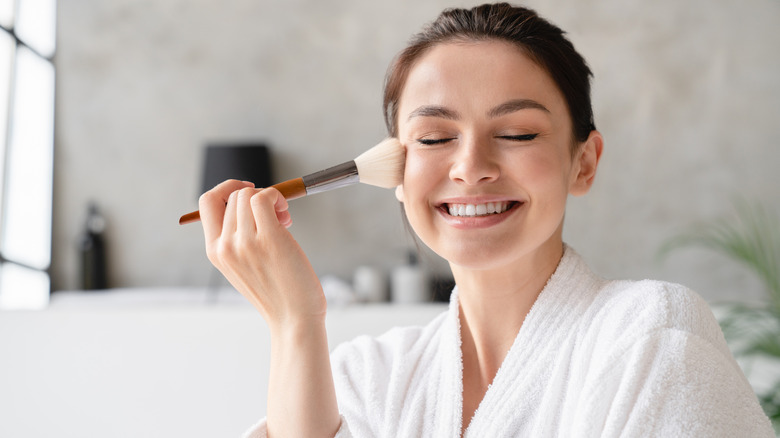 smiling woman applying compact sunscreen