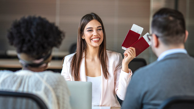 travel agent holding tickets for travelers