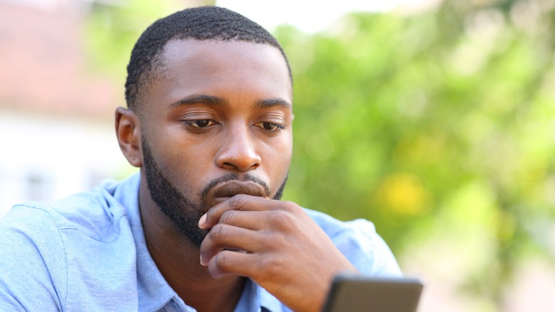 Man looking pensively at phone