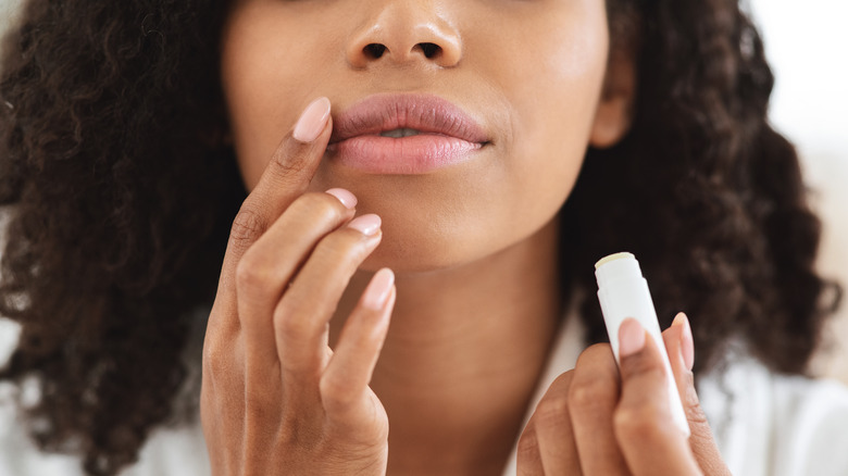 Young woman applying chapstick