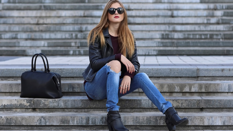 Woman sitting on a staircase in jeans and booties 