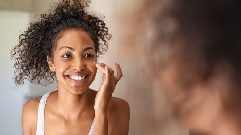 Woman applying lotion to her face