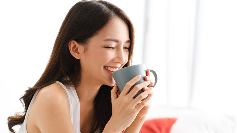 person smiling and holding mug