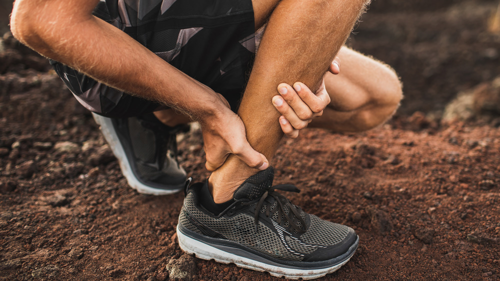 Person crouching while holding ankle and lower leg