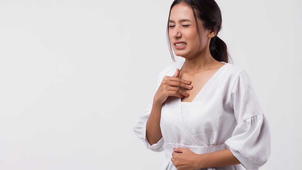 A woman in discomfort holding her stomach and throat