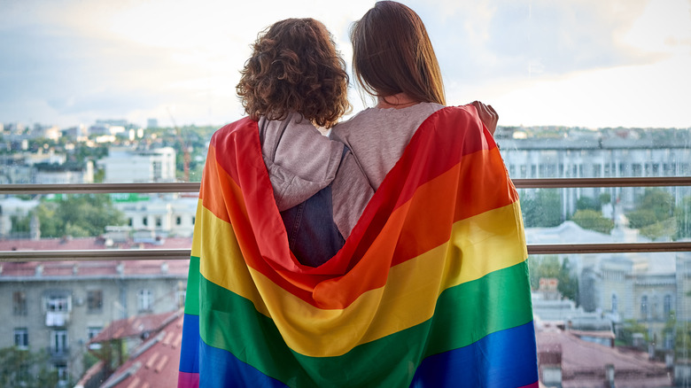 Two people looking at scenery with a pride flag 