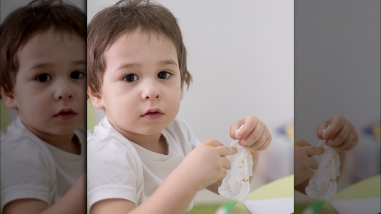 Child wiping hands with disinfecting wipe