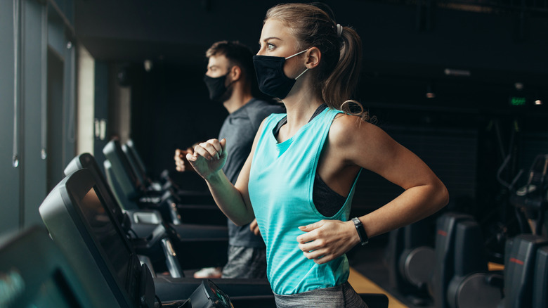 Person running on a treadmill with mask