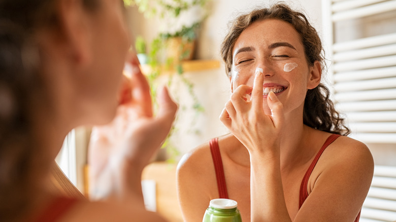 A woman applying face cream