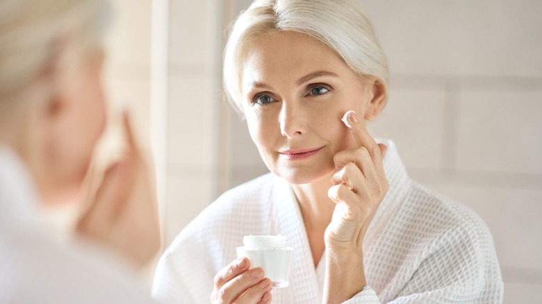 A woman applying face cream