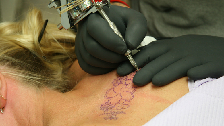 Woman receiving hibiscus tattoo