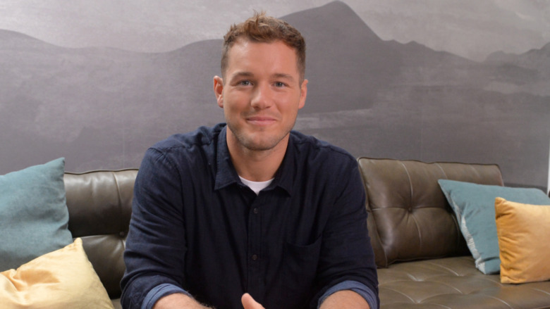 Colton Underwood smiling, sitting on couch