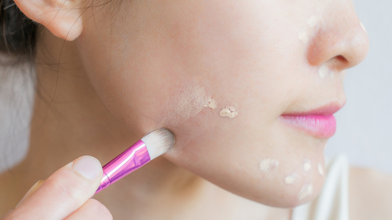 Woman applying concealer on blemishes