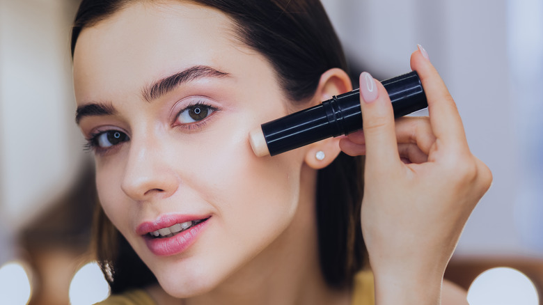 Woman applying a concealer stick