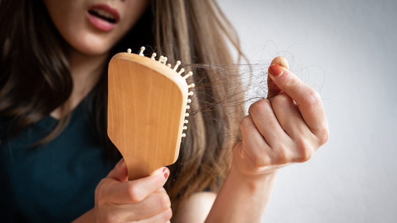 woman holding hairbrush with hair loss