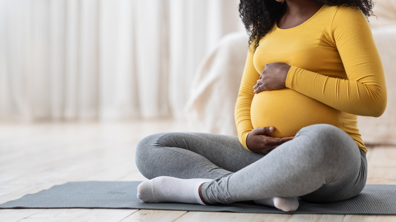 Woman sitting cross-legged holding pregnant stomach