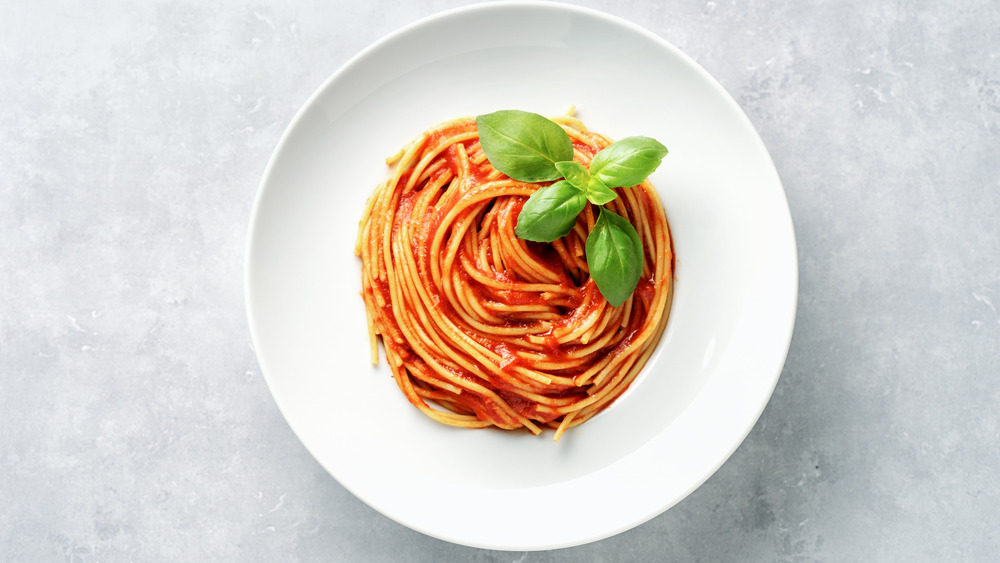 Spaghetti and marinara with basil in a white bowl