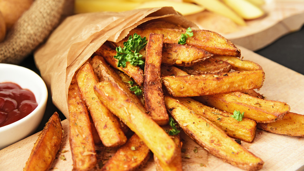 French fries wrapped in paper with condiments