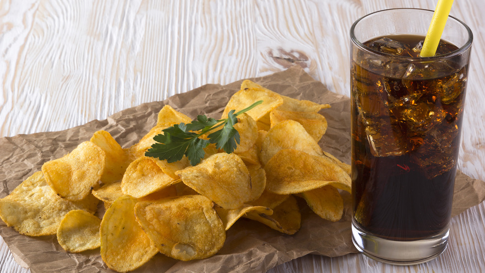 Potato chips and a soft drink on a wooden table