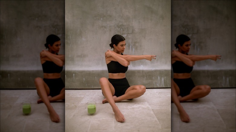 Kourtney Kardashian stretching and a mug of collagen matcha