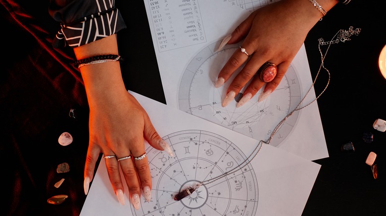 Hands of fortune teller explaining zodiac signs and birth chart