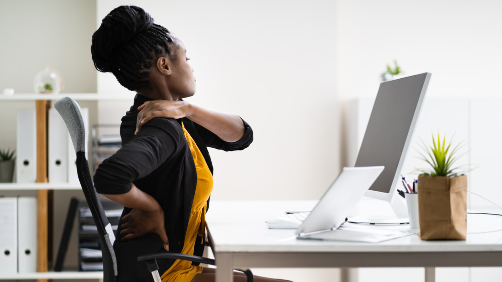 Woman with back pain at her computer