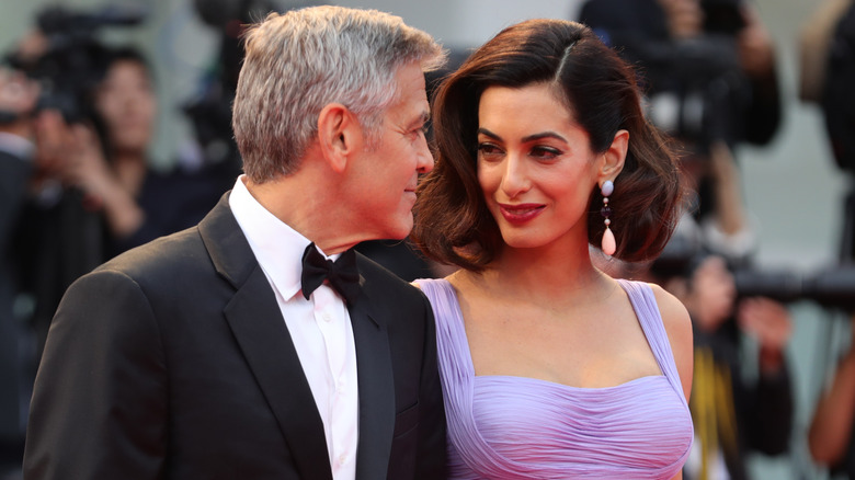 George Clooney and Amal Clooney smiling at each other at an event