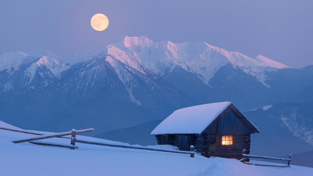 Full moon over snowy mountains and a barn 