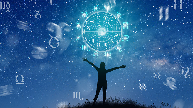 The zodiac wheel and the night sky with a person standing under it 