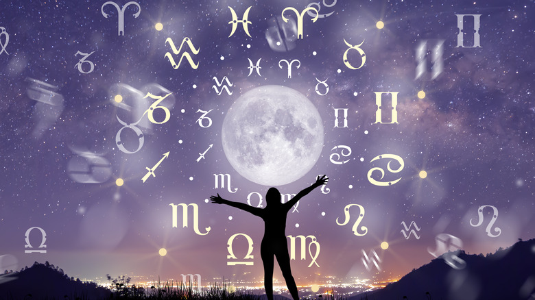 Woman standing in front of moon and zodiac signs