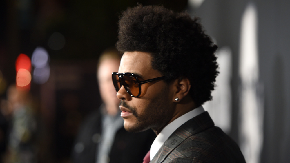 The Weeknd poses on the red carpet with sunglasses